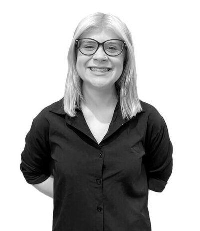 Senior Stylist with a short blonde bob and a black cardigan, showcasing precision and skill in professional hair artistry.