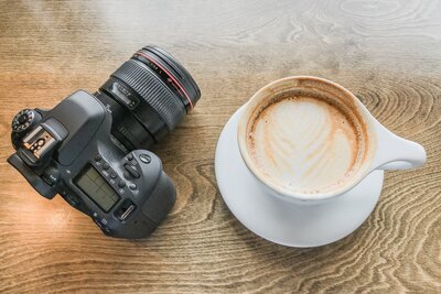latte and camera sitting on a wood table