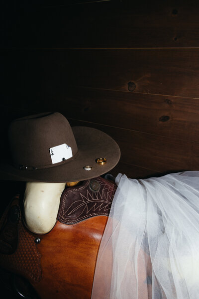 Cowboy hat with wedding rings and veil on saddle