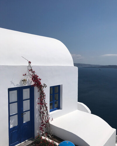 white building with blue door and window frame next to ocean