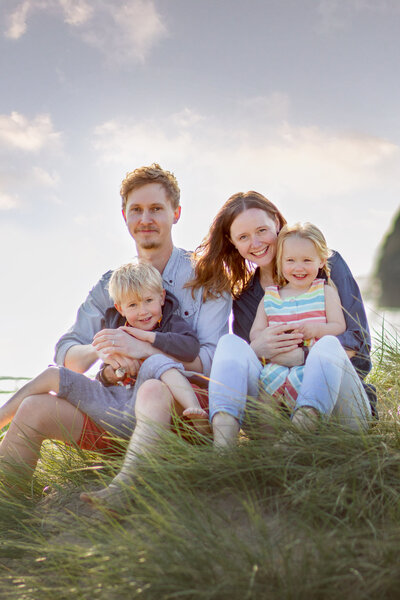 Mother and father kneel down either side of their little girl as she giggles