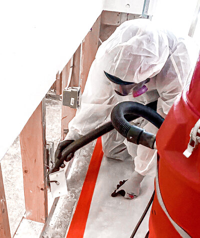 An Everclear team member wearing a white hazmat suit while disinfecting an electric breaker.