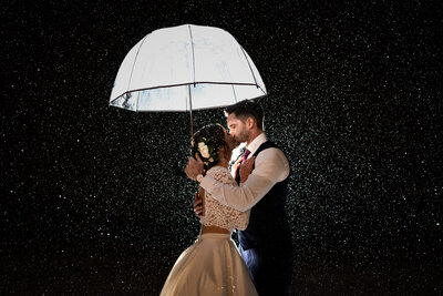 Bride and Groom kissing under an umbrella during a snowstorm