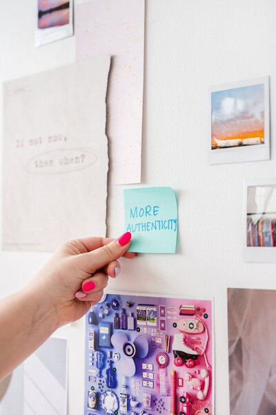 Hand placing a blue sticky note on a collage wall