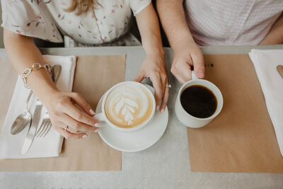 A couple holding a latte and a cup of coffee