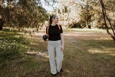 Side shot of Emme Jae Photography looking at camera and smiling at photos just taken