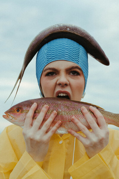 woman holding fish pretending to bite one