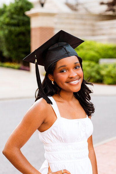 Belmont University graduate wearing white dress smiling at camera wearing graduation cap