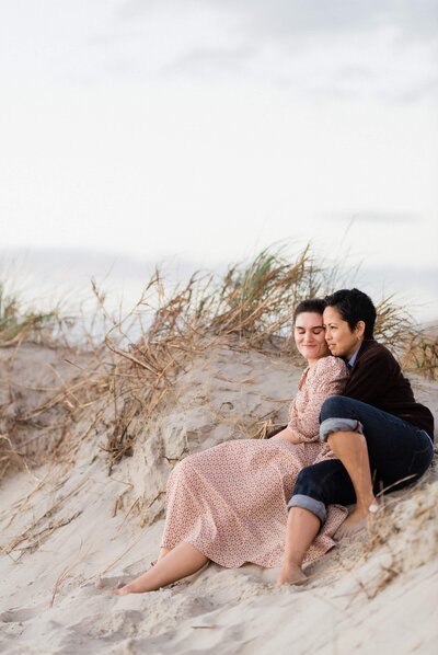 Two girls holding each other on the sand during their engagement photos at brigantine beach