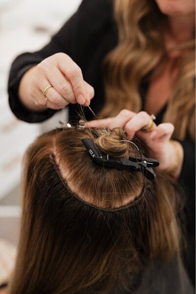 Two hairstylists taking photos of hair extensions