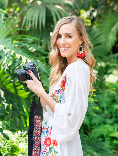 Designer standing in botanical gardens holding her camera