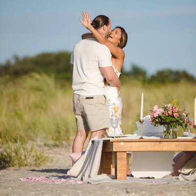 couple embracing each other at the beach with a stunning proposal set up styled proposal setup by Yours Truly, a wedding planner and designer in New Jersey.