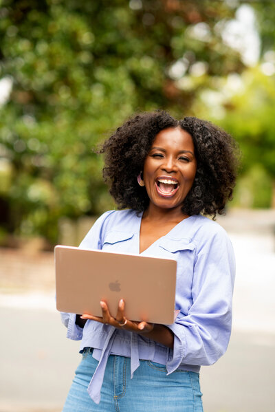 Marjorie Richard smiling and standing outside holding a laptop