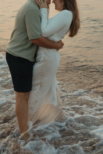 couple embrace on beach during lifestyle photos in pei