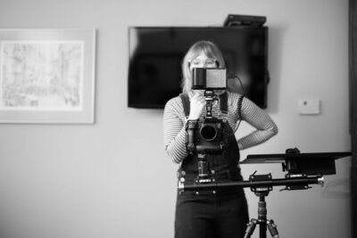 Producer and actor Cassi Angier stands behind a camera on set. 