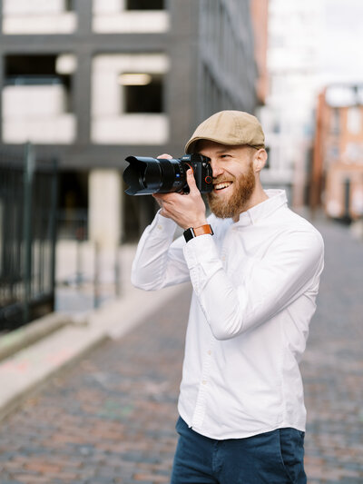 Brad Gillespie smiles while holding his Sony a74 up to his eye in an alleyway just outside of Goodale Park in Columbus