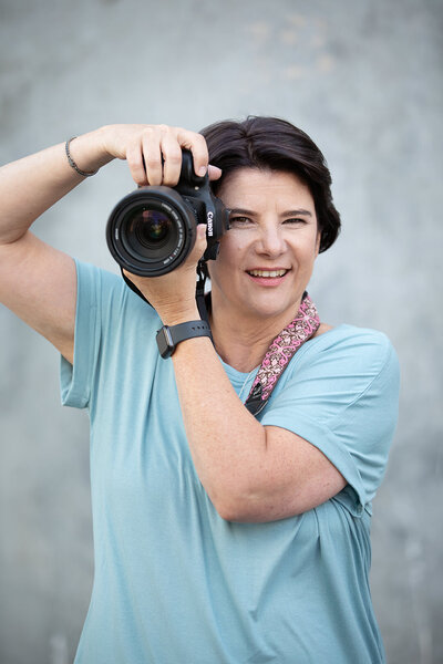 Portrait of photographer posing with camera by her face