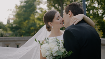 Bride and groom smiling gazing deep into each others eyes outside church. Bride is wearing white dress with lace sleeves and is holding a beautiful bouquet of flowers. Photo taken by Orlando Wedding Photographer Four Loves Photo and FIlm
