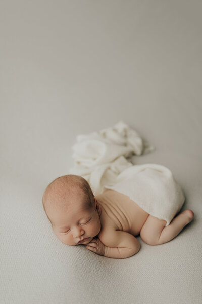 Photo of a newborn baby on a white blanket.