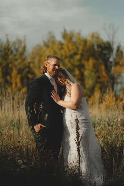 Bride leaning against Groom's shoulder in an Alberta field