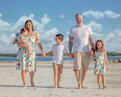 family of five holding hands at the beach