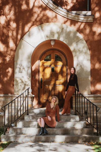 two women posing outside on the steps of a building