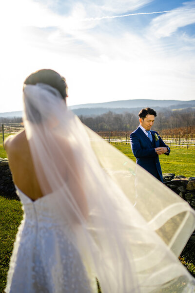 Bride walking up behind groom for emotional first look in open vineyard field in Virginia