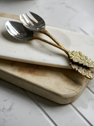 Silver and gold utensils in kitchen on cutting block