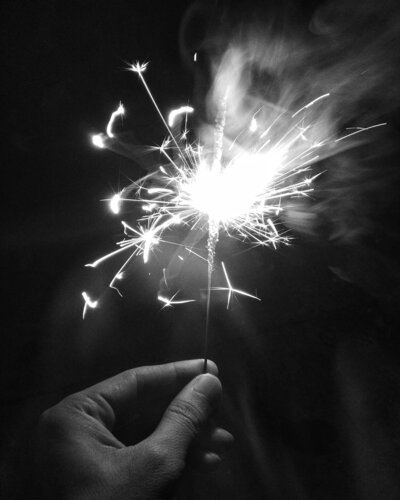 Hand holding sparkler on black background