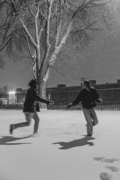 Engaged couple chasing each other in the snow captured by a MN Travel Photographer 