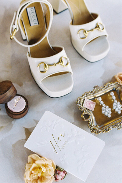 Flatlay of chanel purse and perfume along with rings and shoes.