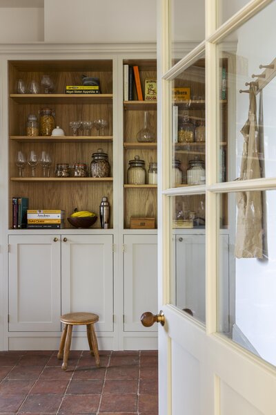 Farmhouse pantry full of kitchen items and a small wooden stool