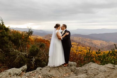 A couple stands in the Shenandoah National Park mountains at sunset after getting married.