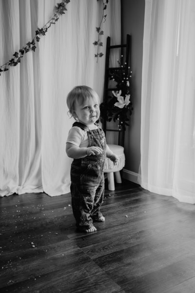Black and white photo of one year old standing and smiling in studio in Annapolis Maryland