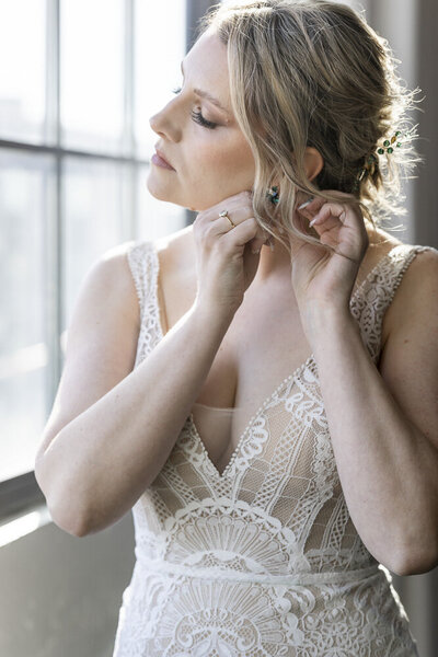 a bride putting on earrings