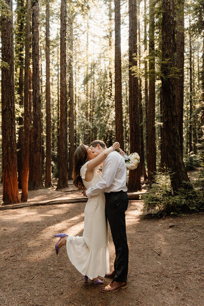 couple hugging in oakland redwoods holding bouquet