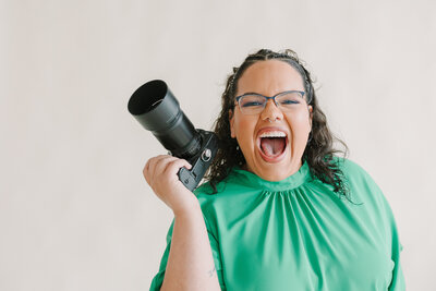A photographer with a big smile on her face holding a camera