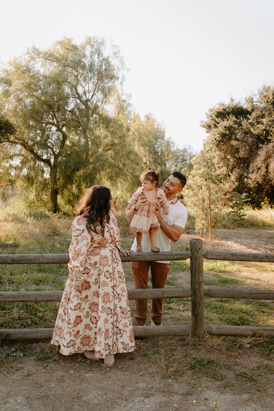 family of 3 leaning on a wooden fence at Horsethief Canyon Park in San Dimas, California 