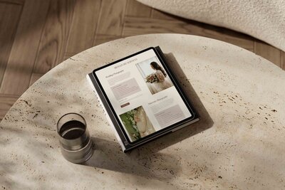 A tablet with wedding and amternity photo on a round minimalist table with a glass of drink