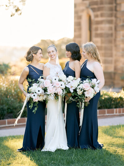 Bridesmaids in navy dresses holding bouquets