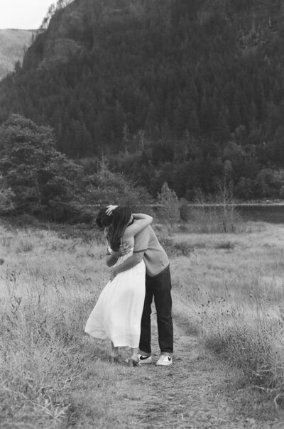 Two lovers embrace in an outdoor Portland, Oregon setting by the water in nature.