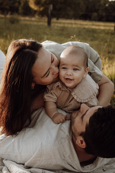 Gezin ligt in het gras met baby voor familiefotoshoot