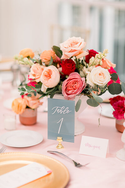 A red. pink and white table arrangement  with a blue table number