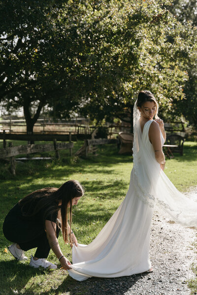 Alissia, fondatrice de nos moments ensemble, organisation d'évènements, en train d'ajuster la robe de la mariée.