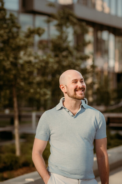 Bald man smiling confidently during an outdoor dating portrait session in downtown Minneapolis, Minnesota, showcasing warm natural light and relaxed expression.