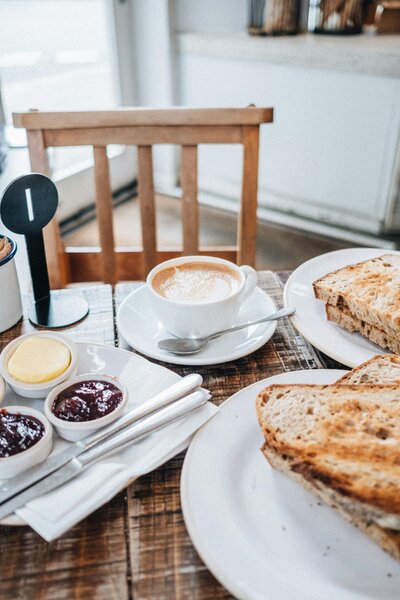 Close up of a breakfast spread on table including coffee, toast, and sides.