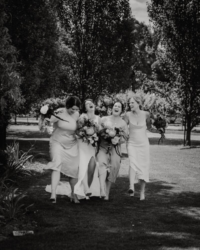 Bride & Bridemaids walking through a garden laughing