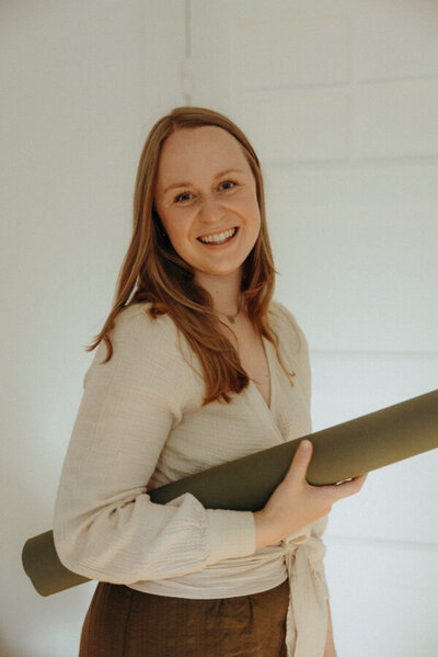 Lächelnde Frau mit Yogamatte in der Hand