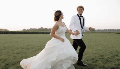 Bride and groom run together in a field