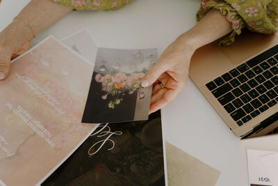 woman holding a picture of flowers and working on laptop